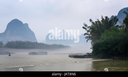 Reisen Sie nach China - Fahrgastschiffe im Nebel über River in der Nähe von Xingping Stadt im Yangshuo County im Frühlingsmorgen Stockfoto