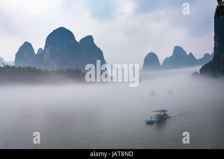 Reisen Sie nach China - Ansicht von Nebel mit Schiffen am Fluss in der Nähe von Xingping Stadt im Yangshuo County im Frühlingsmorgen Stockfoto