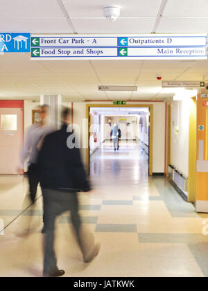 Patienten und Mitarbeiter Spaziergang entlang dem Flur in einer geschäftigen NHS District Hospital Stockfoto