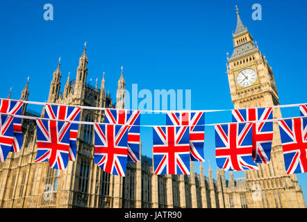 Zwei Reihen der Union Jack Bunting fliegen vor den Houses of Parliament, Westminster Palace mit Big Ben unter strahlend blauem Himmel in London, England Stockfoto