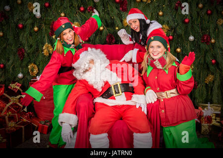 Müde Santa Clause mit Elf Helfer Schlaf Stuhl Weihnachtsdekoration Stockfoto