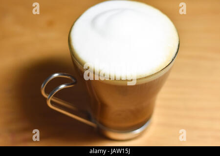 Schaumige Creme auf einen Cappuchino in eine italienische Glasschale mit Edelstahl Griff. Stockfoto