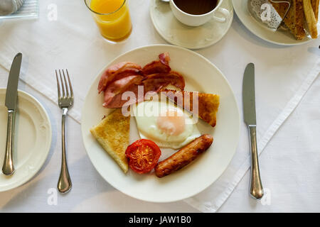 Ulster fry, komplettes Frühstück mit Spiegelei, Speck Speckschnitten, Tomaten, Wurst, Soda Brot und Kartoffeln Brot. Orangensaft und Kaffee zu trinken. Stockfoto