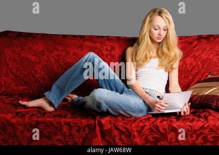 Junges Hübsches Mädchen Mit Langen blonden Haaren so Zuhause Auf Dem Sofa Und Schreibt in Ihr Tagebuch. Stockfoto