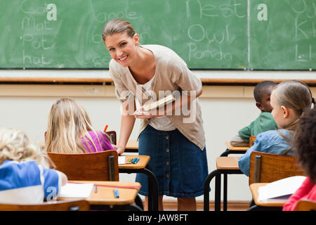 Lächelnde Volksschullehrer neben Schüler Schreibtisch Stockfoto