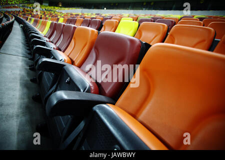 Leere Sitzreihen in verschiedenen Farben in einem Stadion Stockfoto