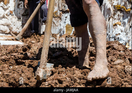 Ein Arbeiter verwendet einen Spaten für Salz Verdampfung Teiche in einer alten Inka Salzbergwerk. Stockfoto