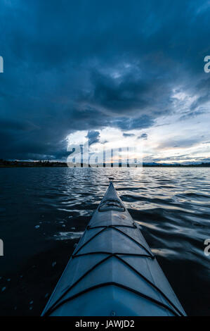 Ein Kanu-Bogen auf einem noch See in den Anden unter Gewitterwolken. Stockfoto