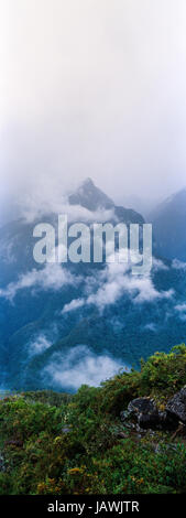 Gewitterwolken verschlingen die steilen bewaldeten Hängen und schroffen Gipfeln der Anden. Stockfoto