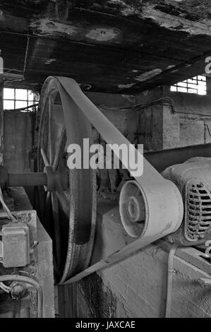 Rostigen Rad Riemenantrieb Maschinen in verlassenen Fabrik innen. Schwarz und weiß. Stockfoto