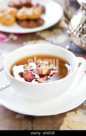 Schwarzer Tee mit Rose Knospen durch einige cookeis Stockfoto