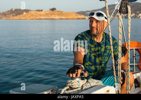 Im mittleren Alter Mann sitzt auf seiner Yacht. Segel- und outdoor-Aktivitäten. Stockfoto