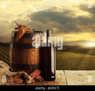 rote Flasche und Wodden Weinfass, Weinberg im Hintergrund Stockfoto