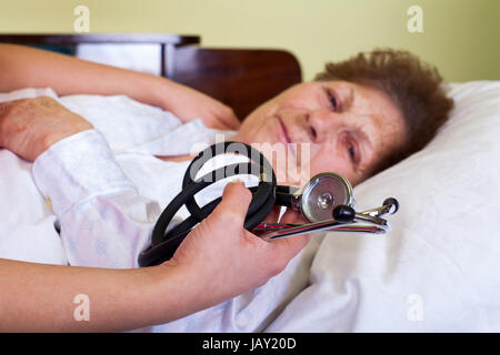 Bild einer kranken alten Frau mit ihrer Pflegeperson Holding ein Stethoskop Stockfoto