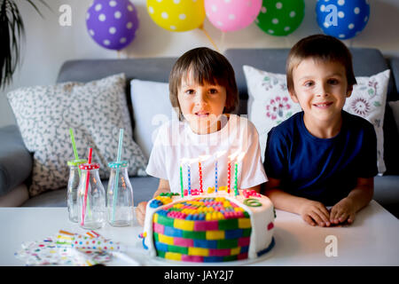 Süßes kleines Kind und sein Bruder, feiert seinen sechsten Geburtstag, Kuchen, Luftballons, Kerzen, Cookies. Kindheit-Glück-Konzept Stockfoto