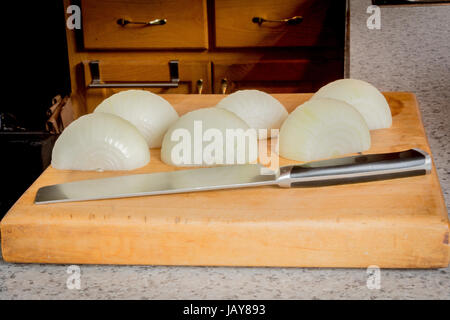 Geschälte Zwiebeln mit einem Messer auf ein Schneidebrett. Stockfoto