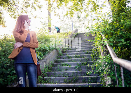 Eine junge Frau am Handy im freien Stockfoto