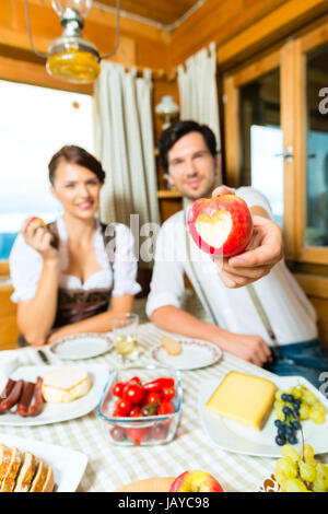 Paar in einem traditionellen Berg Hütte mit einer Mahlzeit, Frühstück mit Obst, Aufschnitt, Käse und Brot Stockfoto