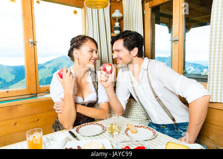 Paar in einem traditionellen Berg Hütte mit einer Mahlzeit, Frühstück mit Obst, Aufschnitt, Käse und Brot Stockfoto