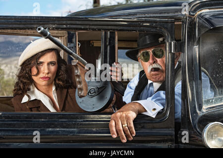 Paar der 1920er Jahre Vintage Gangster warten in einem Oldtimer Stockfoto