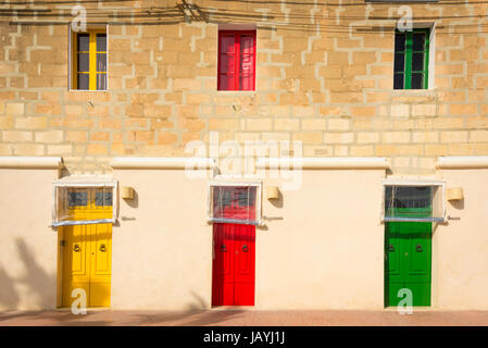 Drei blau hell farbige gelbe und rote Haustüren auf ein Apartment Gebäude in der Fischerei Hafen von Marsaxlokk Malta Stockfoto