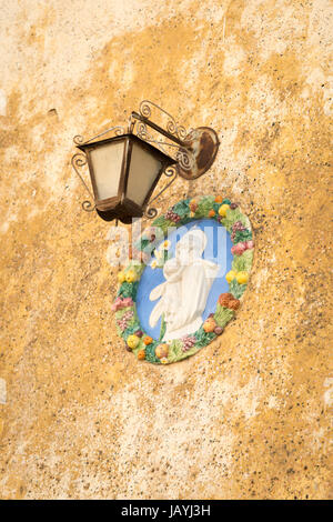 Eine reich verzierte Metall Lampe und Gips Bild der Madonna mit Kind auf einer Hauswand in Malta Stockfoto
