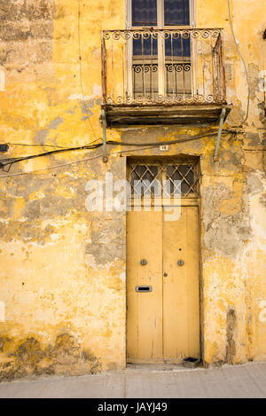 Eine alte Tür auf ein Gebäude in der Fischerei Hafen von Marsaxlokk Malta aus Stein. Ein architektonisches Detail mit blass gelbe Farbe Stockfoto