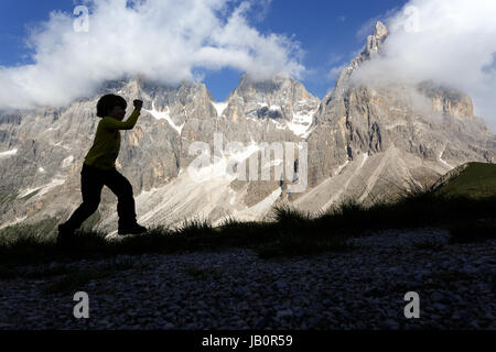 Silhouette eines kleinen Jungen gehen und spielen vor dem Berge, Dolomiten, Italien. Stockfoto