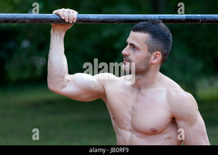 Junge fit Mann tun Übungen am Reck und zeigt seinen muskulösen Körper Stockfoto
