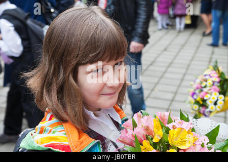 Schulmädchen mit Blumenstrauß geht in die Grundschule im Herbst Stockfoto