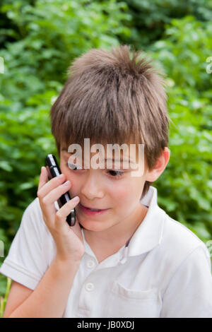 Junge reden über ein Handy im Sommergarten Stockfoto