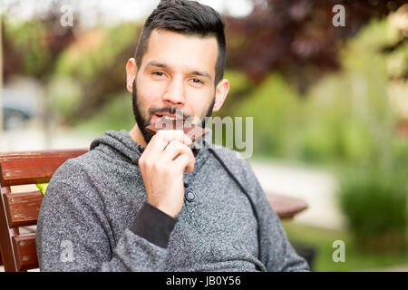 Hübscher bärtiger Mann Schokolade essen Stockfoto