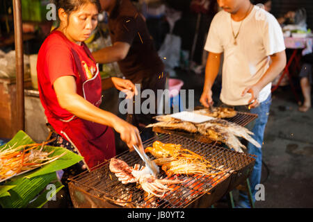 CHIANG MAI, THAILAND - 27 AUGUST: Frau kocht Garnelen und Tintenfische vom Grill am Sonntagsmarkt (Walking Street) am 27. August 2016 in Chiang Mai, T Stockfoto