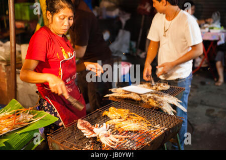 CHIANG MAI, THAILAND - 27 AUGUST: Frau kocht Garnelen und Tintenfische vom Grill am Sonntagsmarkt (Walking Street) am 27. August 2016 in Chiang Mai, T Stockfoto