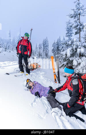 Ski Patrol hilft Frau mit gebrochenem Bein im Schnee liegend Stockfoto
