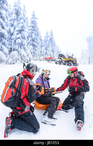 Ski Patrol Team Rettung Frau Skifahrer mit gebrochenen arm Stockfoto