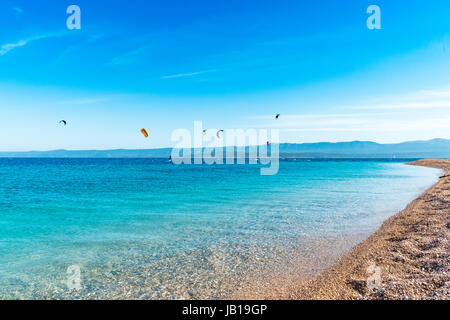 Ebene Flachschuss des Goldenen Horns Wahrzeichen auf der Insel Brac in Kroatien. Kitesurfer im Hintergrund beleben die malerische Szenerie. Stockfoto