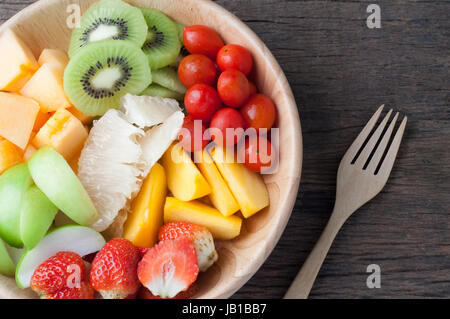 Küchentisch mit verschiedenen Früchten auf Holzplatte und Gabel, Gruppe von Obst Salat - gesunde Ernährung und Diät essen, Konzept der Gesundheitsversorgung, Bild f Stockfoto