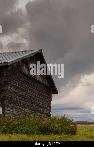 Ein bewölkter Tag an der ländlichen Finnlands. Die alte Scheunenhaus steht einsam gegen den aufkommenden Sturm. Stockfoto