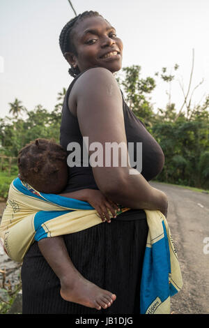 MALANZA/SAO TOME - 2. Januar 2016 - Porträt der Afrikanerin mit Sohn auf dem Rücken, gebürtig aus Sao Tome Stockfoto