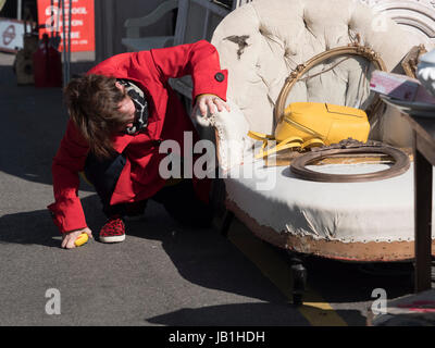 Ein Käufer in hellen roten Mantel untersucht eine Chaise Longue oder Couch Polster am Sunbury Antiquitäten Messe Kempton Park in der Nähe von London England Stockfoto