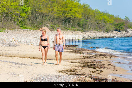 Stenshuvud Nationalpark, Schweden - 20. Mai 2017: ökologische Dokumentarfilm. Erwachsenes paar zu Fuß in Richtung Sie am Strand. Buchenwald im Hintergrund. Stockfoto