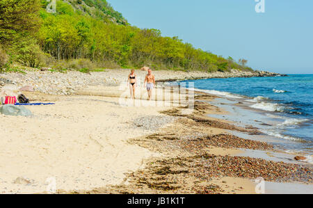 Stenshuvud Nationalpark, Schweden - 20. Mai 2017: ökologische Dokumentarfilm. Erwachsenes paar zu Fuß in Richtung Sie am Strand. Buchenwald im Hintergrund. Stockfoto