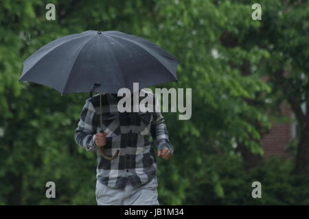 Mann mit schwarzen und weißen Hemd über seinen Kopf mit einem Regenschirm Stockfoto