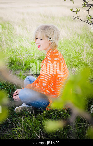 Close-up Portrait im freien junge schöne Mädchen in einer orange Hipster blond hell fröhlich Dot Bluse, lächelnd rote volle Lippen auf die Zeitmessung Stockfoto