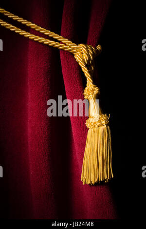Roter Samtvorhang mit Quaste. Schwarzer Vorhang isoliert hautnah Stockfoto