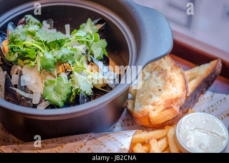 Hoegaarden Muscheltopf gehackt, Koriander, Fenchel, Zitronenschale und Hoegaarden Bier Pommes frites Stockfoto