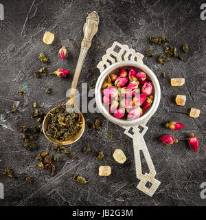 Rosenknospen in einem kleinen Metall Sieb trocknen, und grüner Tee in den Löffel und karamellisierten braunen Zucker trocken. Stockfoto