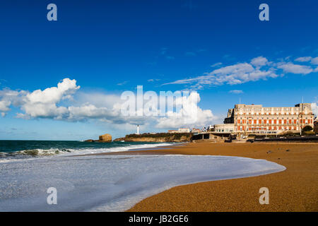 Die Grande Plage Form Biarritz bei teilweise bewölktem Himmel blau. Berühmte Hotel du Palais im Hintergrund Stockfoto