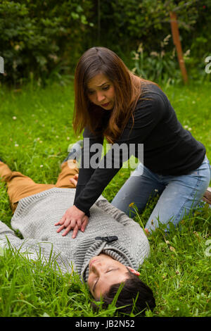 Schöne Frauen, erste Hilfe, Herz-Lungen-Wiederbelebung, in einem Rasen-Hintergrund zu geben. Stockfoto